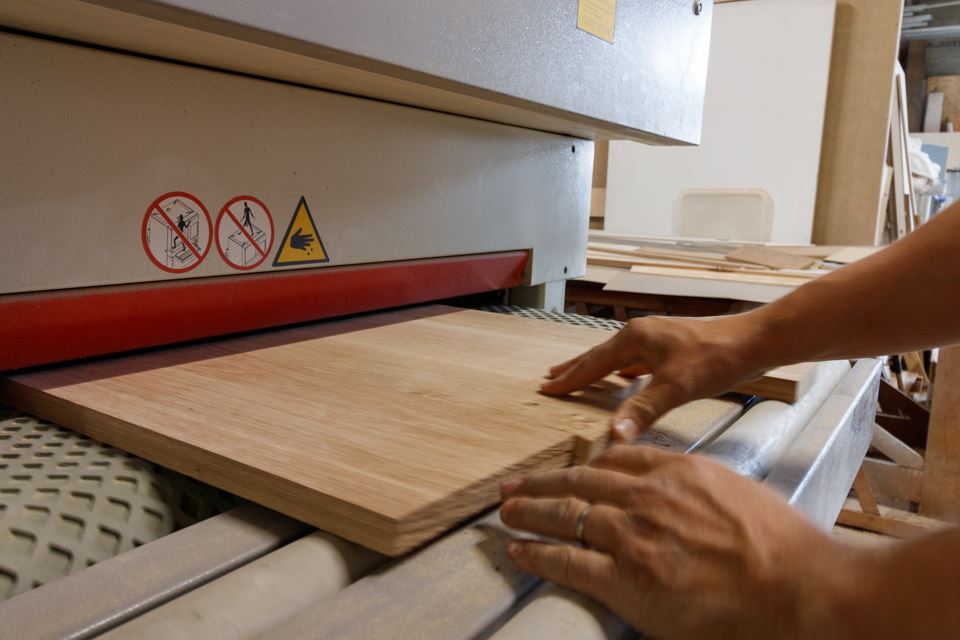 ébéniste en train de poncer du bois